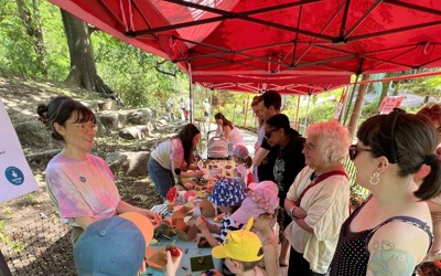 Kids and adults gathered around a long table, interacting with staff and handling fossils