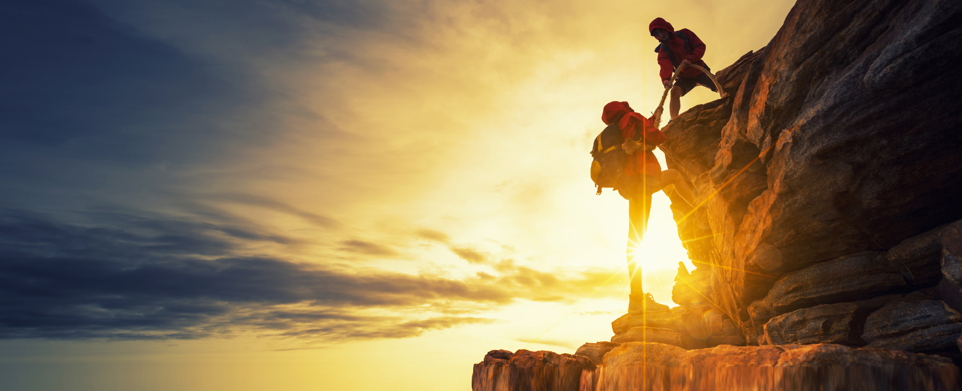 Image first climber helping second climber over a rocky ledge Shutterstock 760304731