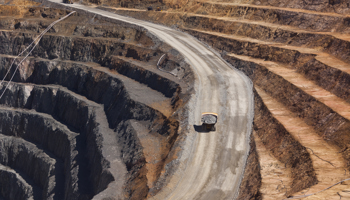 "An open-pit coal mining site with heavy machinery transporting materials along a winding road."