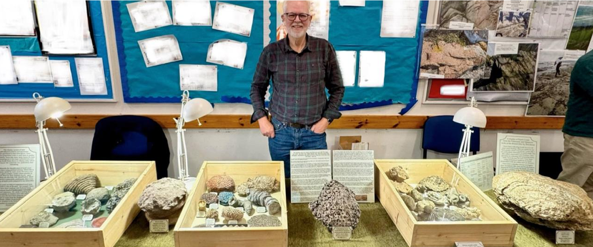 man stood behind a table which has boxes of rocks on it